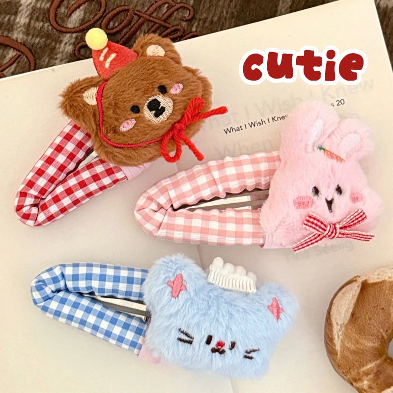 Three kawaii plush animal hair clips with checkered patterns on a book page.