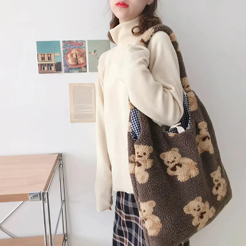 Person holding a brown tote bag with teddy bear patterns in a room.