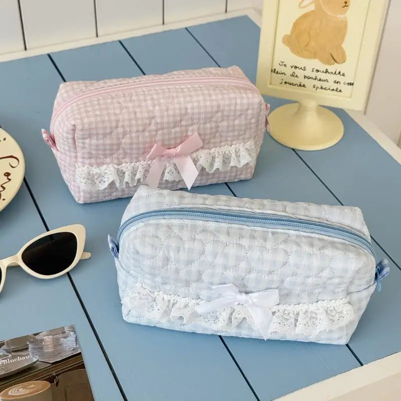 Two lace-trimmed pencil case on a blue wooden surface with sunglasses and a coaster.