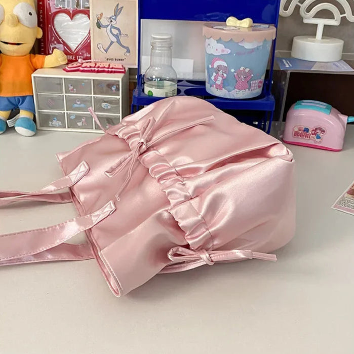 Pink shiny bag on a table with various items in the background