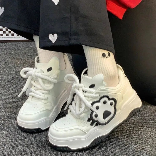 White sneakers with paw print design on grey floor