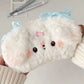 Plush white puppy pencil case  with a blue bow held by a person.