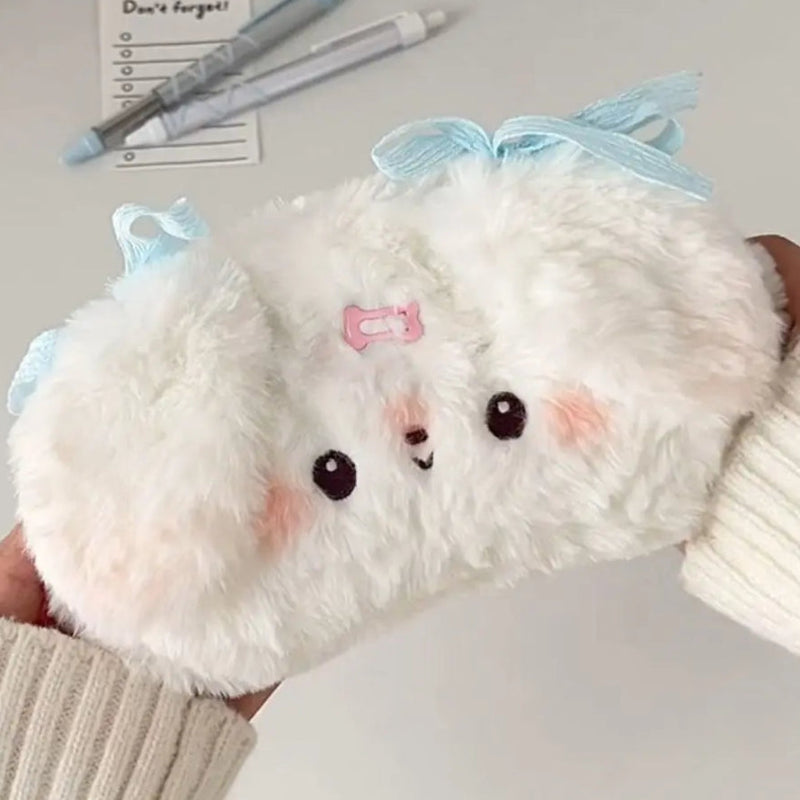 Plush white puppy pencil case  with a blue bow held by a person.