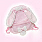 Pink bunny-shaped backpack with white ears and bow on a pink polka dot background