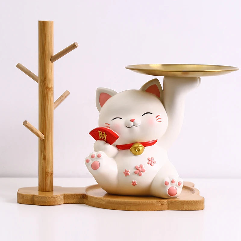 White cat-shaped ceramic figure with a red bow and bell, standing on a wooden base.