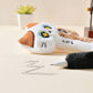 Plush cat pens on a surface with writing