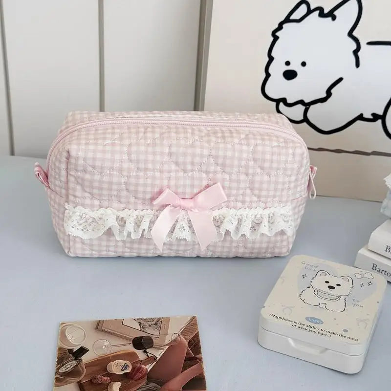 Pink checkered pencil case with lace details on a white surface.