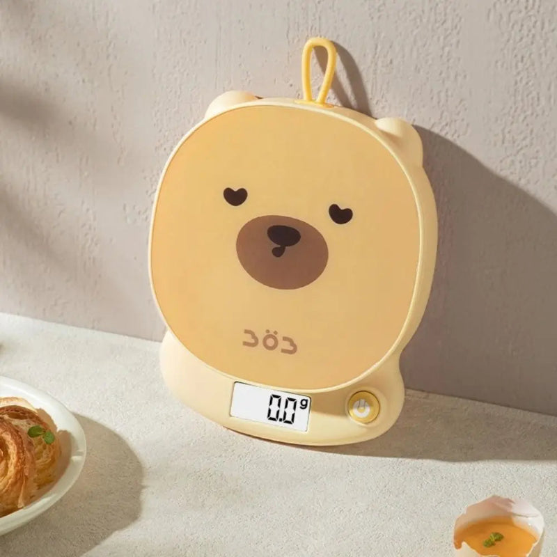 Yellow bear-shaped digital scale on a light surface with a neutral background