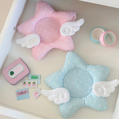 Two star-shaped coasters with angel wings on a light surface with stationery items.