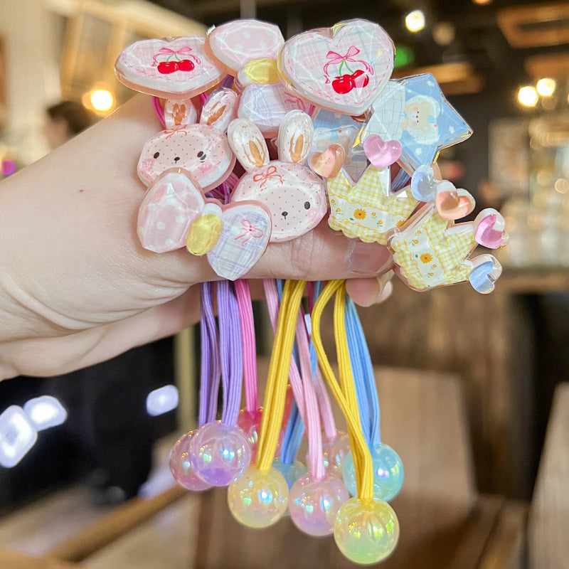 Colorful hair ties with cartoon character designs held by a hand.