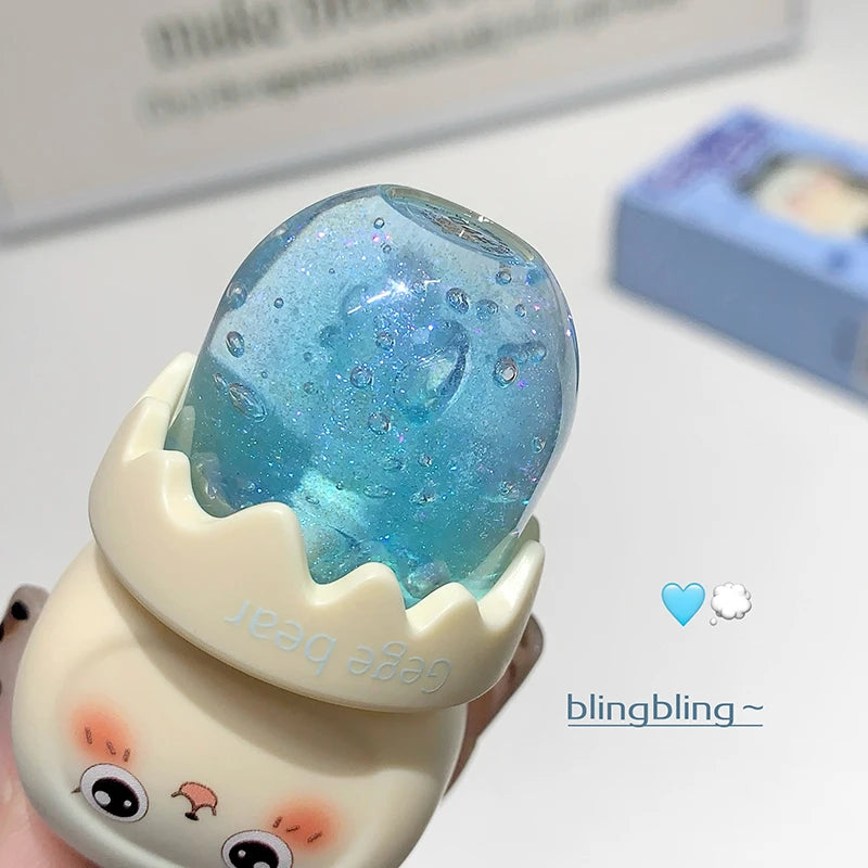 kawaii character-shaped blue glittery lip oil with cartoon face on a light background