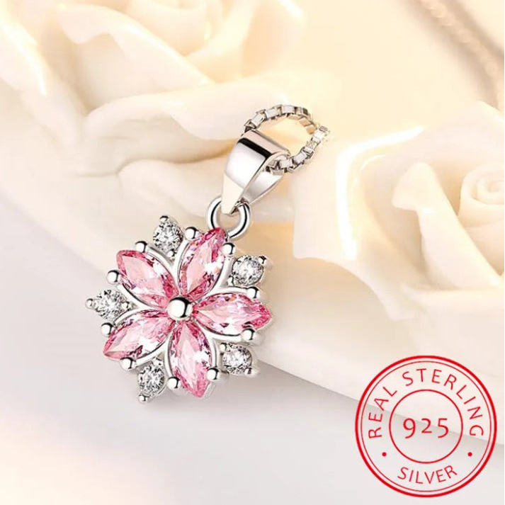 Sakura Cherry Blossom Necklace the hot pink version is displayed on a pastel pink cloth slightly crumpled up to display the pendant more effectively.