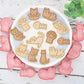Cat-themed cookie cutters on a white plate with a wooden background