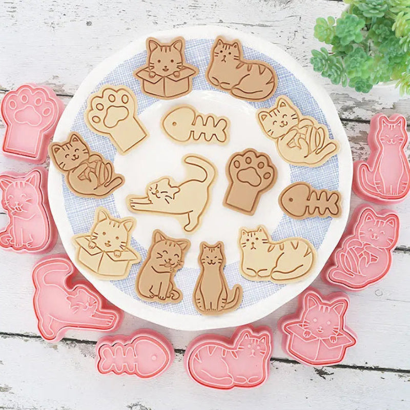 Cat-themed cookie cutters on a white plate with a wooden background