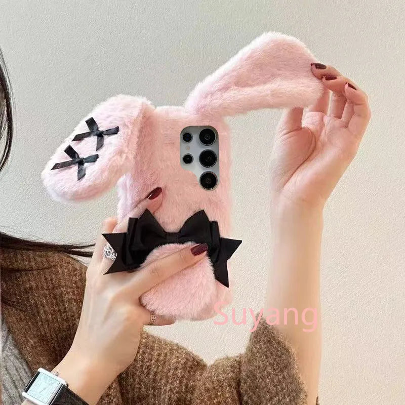 the woman is holding the Kawaii Plush Bunny Samsung Phone Case to display the back of the case , showing off the floppy pink bunny ears.