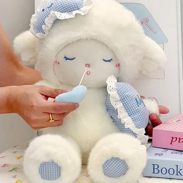 White lamb plushie with blue checkered details held by a hand.