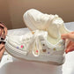 White sneakers with decorative elements held by a hand on a light background