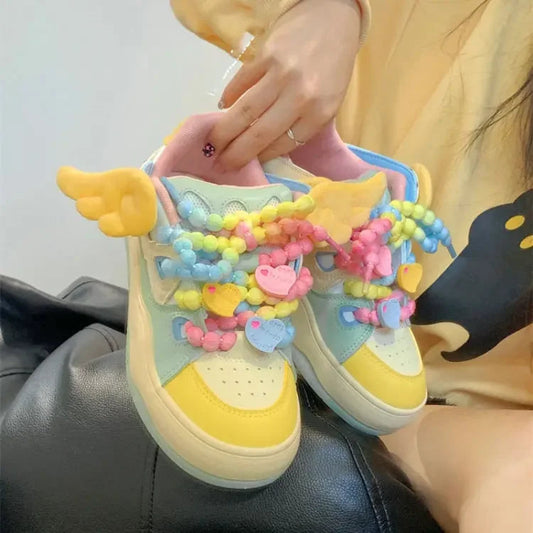 Angel on a rainbow platform sneakers, being displayed in front of a yellow hoodie and white wall.