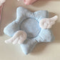 Blue star-shaped coaster with white polka dots and angel wings on a beige background