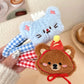 Two plush animal hair clips, one blue and one brown, held by a hand on a blurred background.