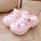 Pink sandals with decorative star and bow elements on a wooden floor