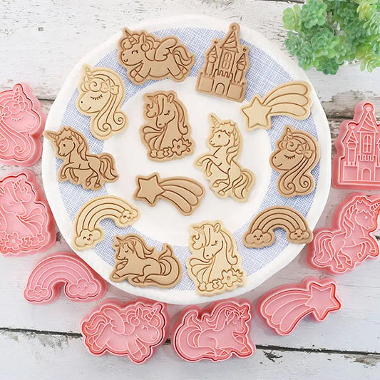 Set of unicorn-themed cookie cutters on a white plate with a wooden background.