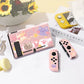 Pink gaming console and controllers with cat-themed design on a light surface.