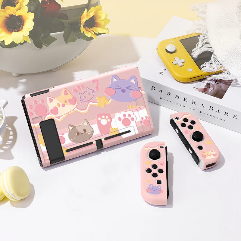 Pink gaming console and controllers with cat-themed design on a light surface.