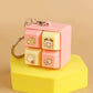 Cute pink and yellow keychain with cartoon designs on a beige background
