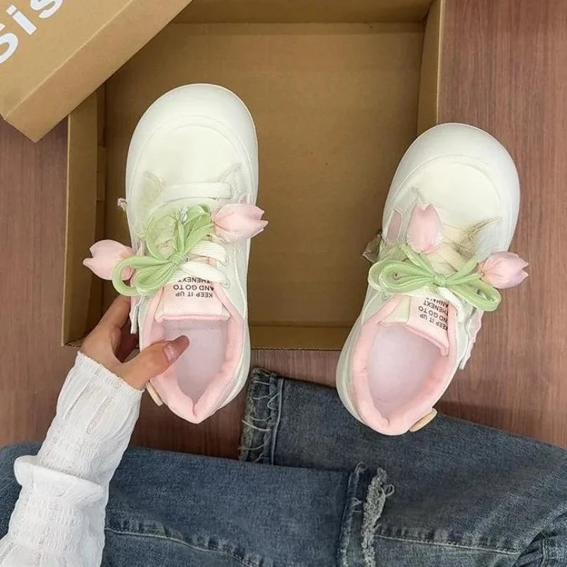 White sneakers with floral decorations inside a cardboard box.