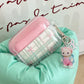 Pink and clear kawaii air pod case with a keychain on a green surface