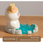 Cute resin figurine of a cat in a onsen with a yellow towel on its head on a wooden surface.
