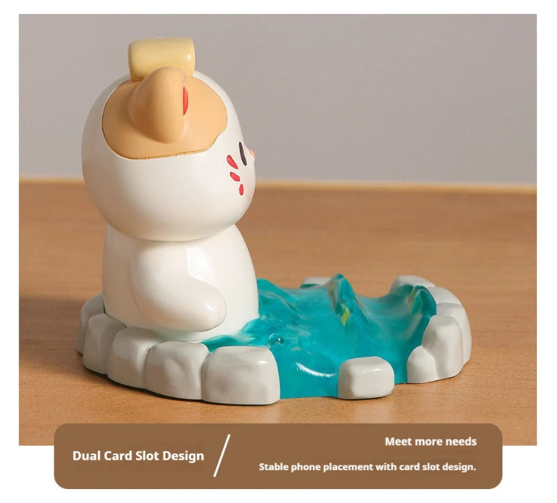 Cute resin figurine of a cat in a onsen with a yellow towel on its head on a wooden surface.