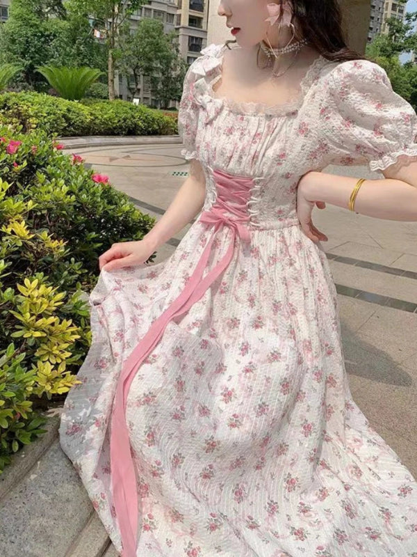 Woman wearing a floral dress with a pink ribbon in an outdoor setting