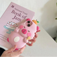 Pink capybara phone case with kawaii design held over a book titled 'National Trust Book of Jam'.