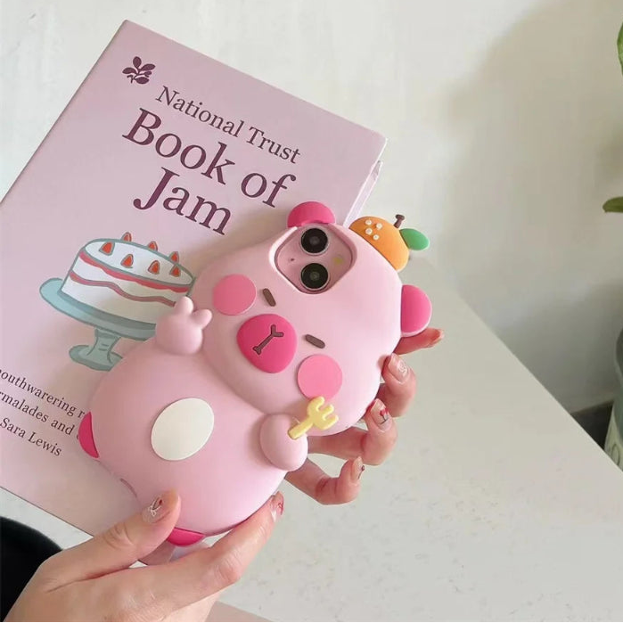 Pink capybara phone case with kawaii design held over a book titled 'National Trust Book of Jam'.