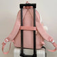 pink neko backpack displayed by a white wall on a luggage handle 