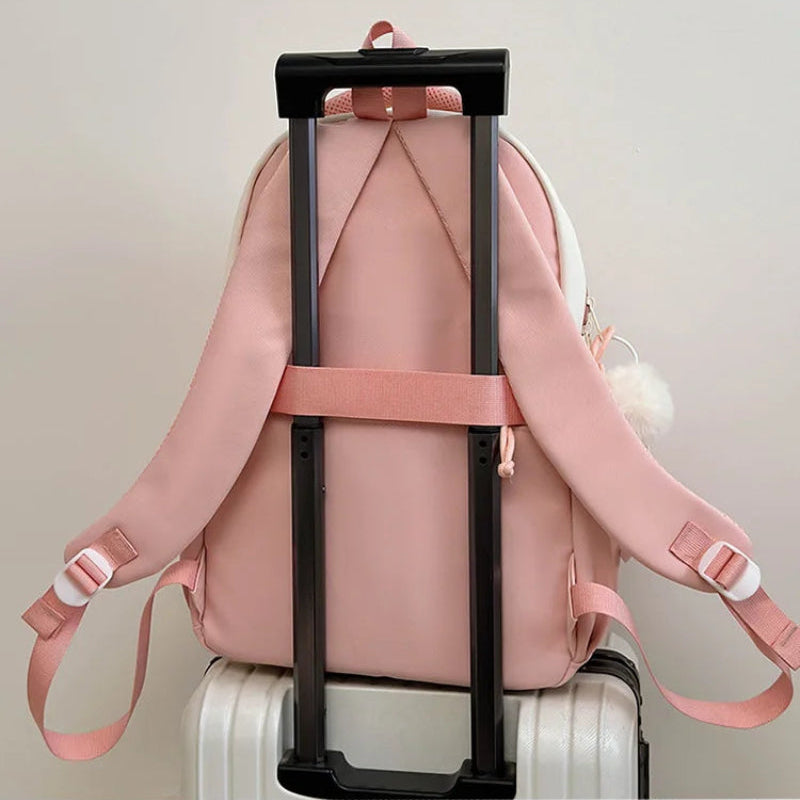 pink neko backpack displayed by a white wall on a luggage handle 