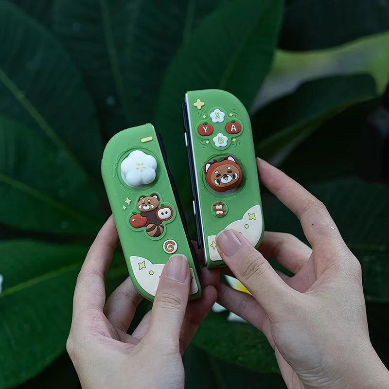 Two green gaming controllers with cartoon red panda designs held by hands against a leafy background
