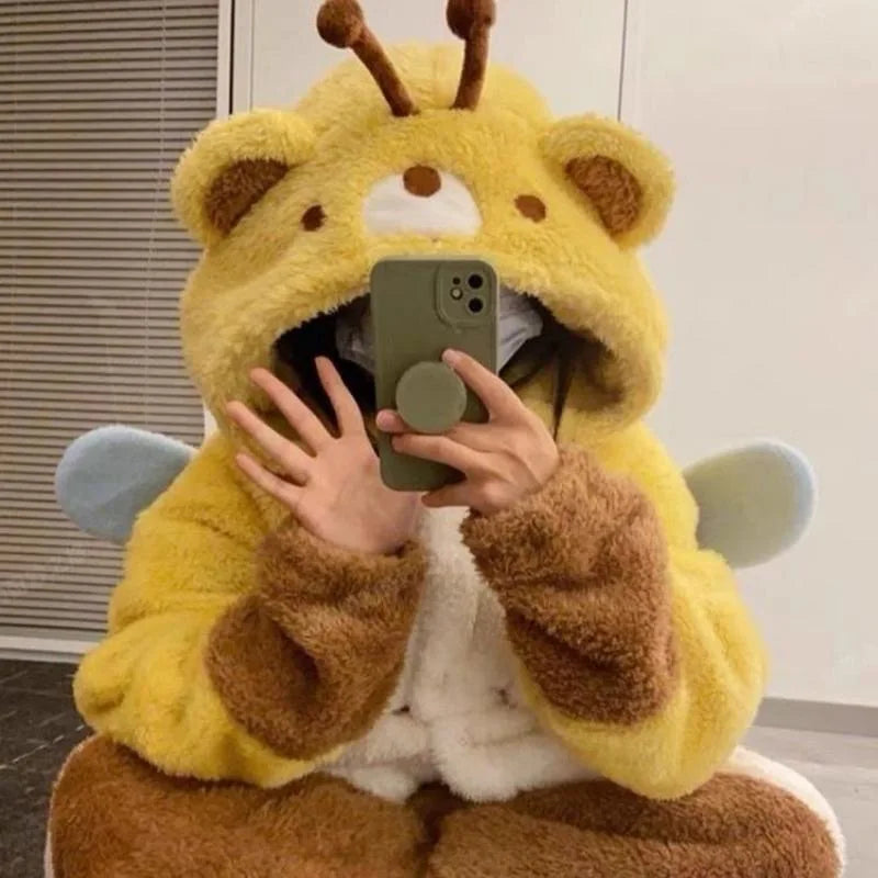 Person wearing a yellow and brown plush bear onsie holding a phone.