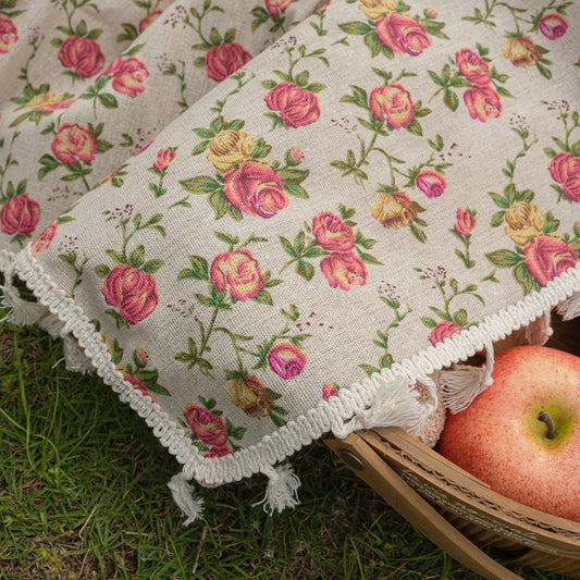 Floral-patterned fabric with pink roses and green leaves on a grassy background