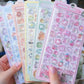 Colorful sticker sheets with cartoon characters held by a hand