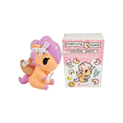 Unicorno toy with pink hair and a box labeled 'Fortune Cookie Unicorno' on a white background