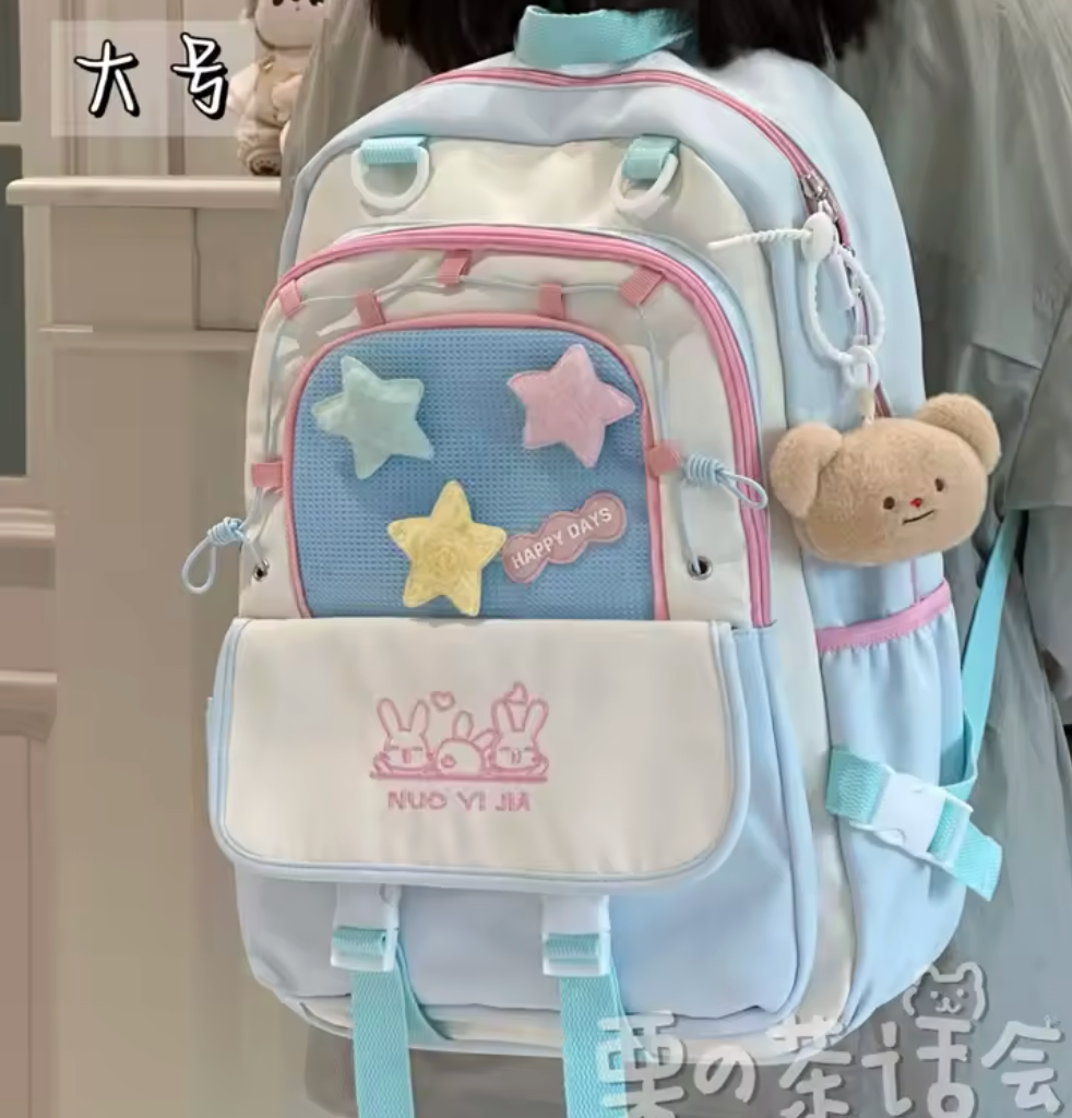 Pastel-colored backpack with star designs and a teddy bear charm on a neutral background.