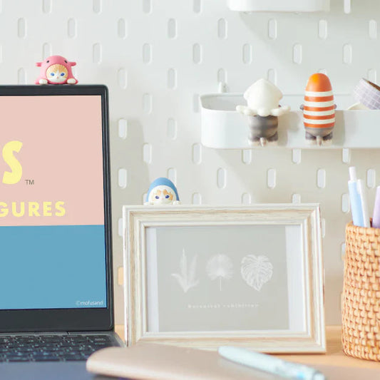 Laptop on a desk with 'mofusand' branding, surrounded by decorative items.