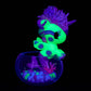 Glowing green and purple unicorn blind box figurine in a clear container on a black background