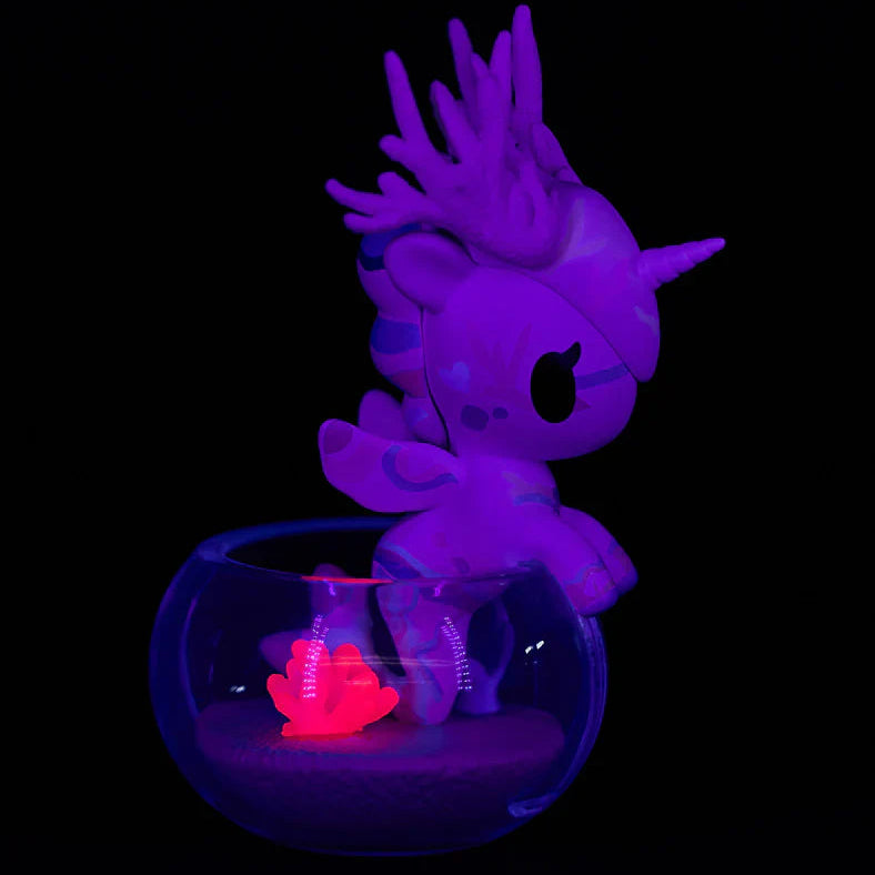 Glowing purple unicorn figurine inside a transparent bowl on a black background