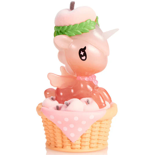 Kawaii Unicorn Blind Box Figure with a pink apple on top, sitting inside a basket of pink flowers on a white background.