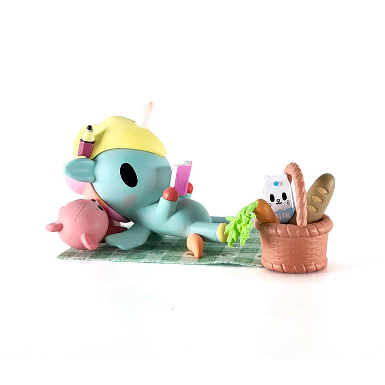 Kawaii Unicorn Blind Box figure of a unicorn laying on a towel with a basket of food items.
