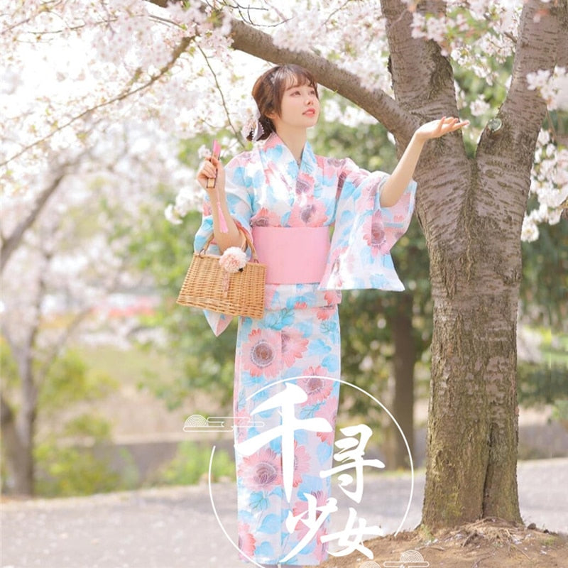 Model Wearing Kawaii Pink and Blue Floral Yukata Surrounded by Cherry Blossoms